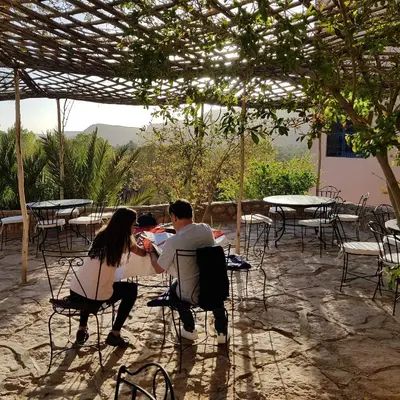 a man and woman sitting at a table under a pergola at Maison D'hotes Sahara in Aoufous