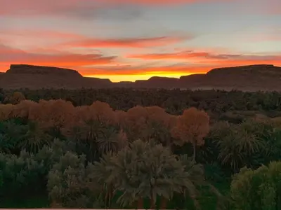 a sunset in the desert with mountains in the background at Maison D'hotes Sahara in Aoufous