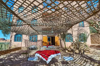 a patio with a table and chairs under a pergola at Maison D'hotes Sahara in Aoufous