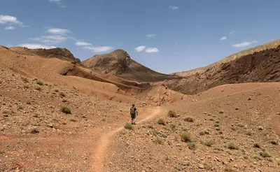 a man walking on a dirt road in the desert at Maison D'hote Chez La Famille in Tamellalt