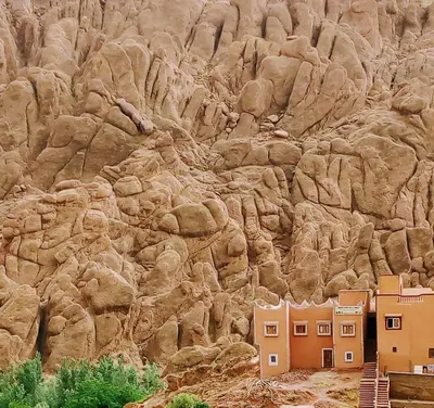 a rocky mountain with houses in front of it at Maison D'hote Chez La Famille in Tamellalt