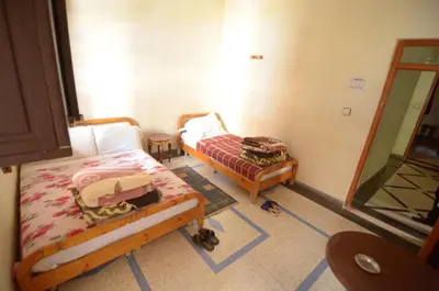 a bedroom with two beds and a cat in it at Hotel Imilchil in Zaouiat Cheikh