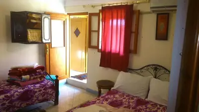 a bedroom with a bed and a window and a door at Hotel Imilchil in Zaouiat Cheikh