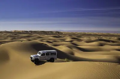 a white truck driving through the desert at Aladdin Desert Camp - Mhamid Erg Chigaga Escape in El Gouera
