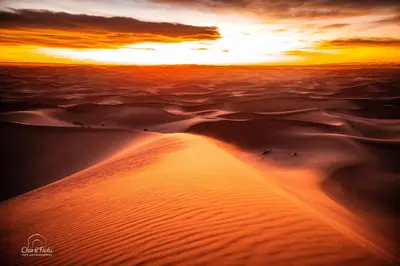 a sunset over the sand dunes in the desert at Aladdin Desert Camp - Mhamid Erg Chigaga Escape in El Gouera