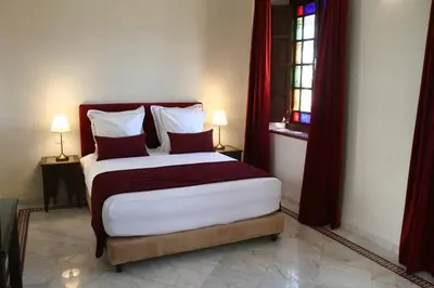 a bedroom with a large bed with red curtains at Riad Batchisarai in Fès