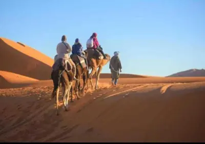 a group of people riding camels in the desert at berber sahara in Zagora