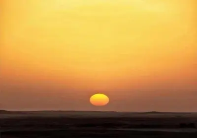 a sunset over the ocean with the sun in the sky at berber sahara in Zagora