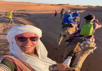 a woman riding a camel in the desert at berber sahara in Zagora