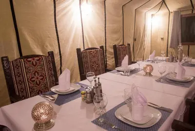 a table with white tablecloths and napkins on it at Luxury Desert Camp Amanar in Merzouga
