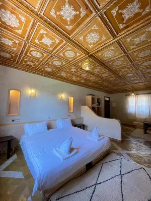 a bedroom with a large bed with a coffered ceiling at Bab Rimal - Desert Hotel in M'hamid El Ghizlane in Mhamid