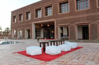 a brick building with two white chairs and a table at Bab Rimal - Desert Hotel in M'hamid El Ghizlane in Mhamid