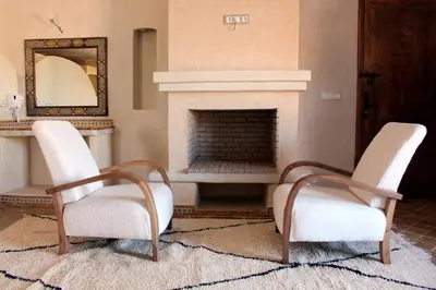 a living room with two chairs and a fireplace at Bab Rimal - Desert Hotel in M'hamid El Ghizlane in Mhamid
