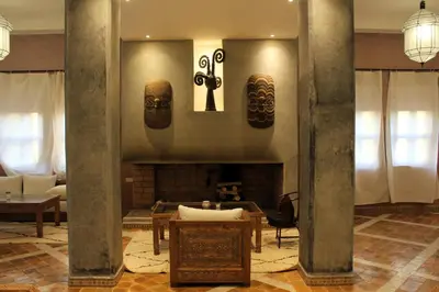 a living room with a fireplace and two masks on the wall at Bab Rimal - Desert Hotel in M'hamid El Ghizlane in Mhamid