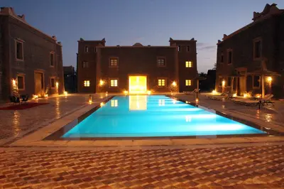 a large swimming pool in a courtyard at night at Bab Rimal - Desert Hotel in M'hamid El Ghizlane in Mhamid