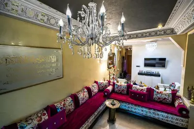 a living room with a red couch and a chandelier at Appartement Luxe Simo in Fès