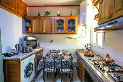 a kitchen with a washing machine and a table with chairs at Appartement Luxe Simo in Fès