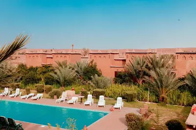 a resort with a pool and lounge chairs and a building at Maison D'hôte Amridil in Skoura