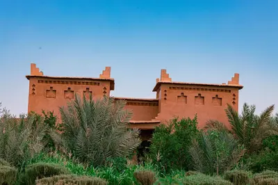 a red brick building with trees in front of it at Maison D'hôte Amridil in Skoura