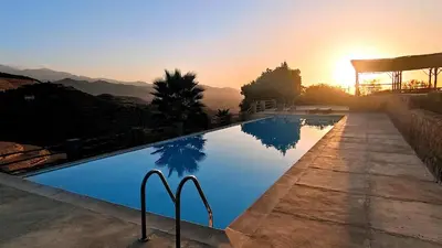 a swimming pool with the sunset in the background at Le Douar Berbere in Ourika