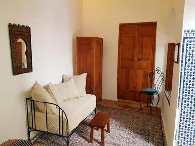 a living room with a white couch and a wooden door at Riad Inspira in Meknès