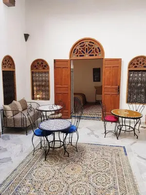 a room with tables and chairs and a couch at Riad Inspira in Meknès
