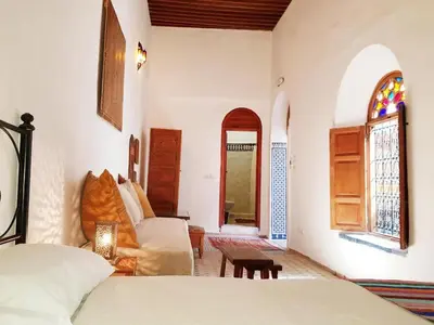 a bedroom with a bed and a couch and a window at Riad Inspira in Meknès