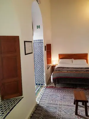 a bedroom with a bed and a wooden door at Riad Inspira in Meknès