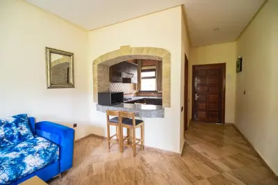a living room with a blue couch and a kitchen at Résidence Hôtelière Le Diamant Vert in Fès