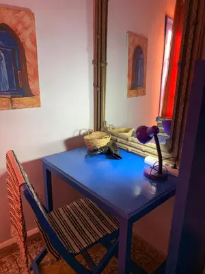 a blue table with a lamp and a chair at Chez Youssef in Merzouga