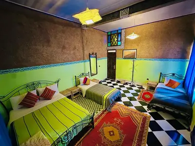 a room with two beds and a checkered floor at La Petite Kasbah in Zagora