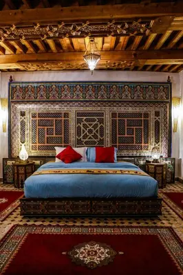 a bedroom with a large bed with a blue bedspread at Riad Al Fassia Palace in Fès