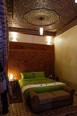 a bedroom with a green bed with a ceiling with a painting at Riad Al Fassia Palace in Fès