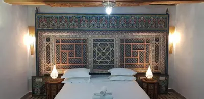 a bedroom with a bed and a wall with an oriental pattern at Riad Al Fassia Palace in Fès
