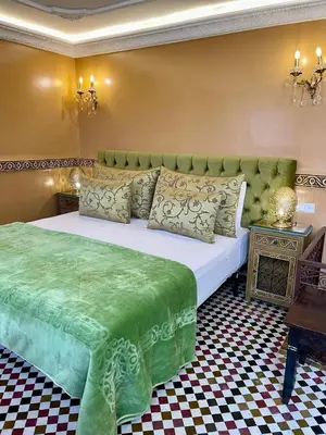 a bedroom with a large bed with a green blanket at Riad Ibn Battouta & Spa in Fès