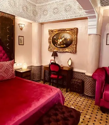 a bedroom with a red bed and a painting on the wall at Riad Ibn Battouta & Spa in Fès
