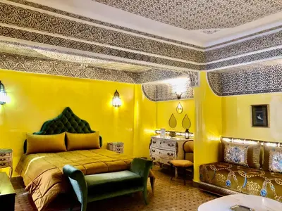 a bedroom with yellow walls and a bed and a couch at Riad Ibn Battouta & Spa in Fès