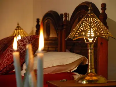 a bedroom with a bed with a lamp on a table with candles at Riad Ibn Khaldoun in Fès