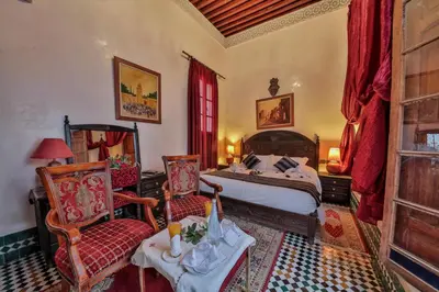 a bedroom with a bed and two chairs at Riad Ghita in Fès