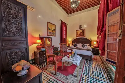 a bedroom with a bed and a table and chairs at Riad Ghita in Fès