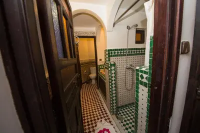 a bathroom with a shower and a toilet and a door at Riad Ghita in Fès