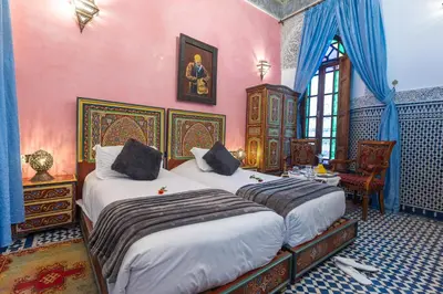 two beds in a room with pink walls at Riad Ghita in Fès