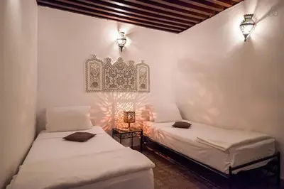 two twin beds in a room with lights on the wall at Riad Jamaï in Fès
