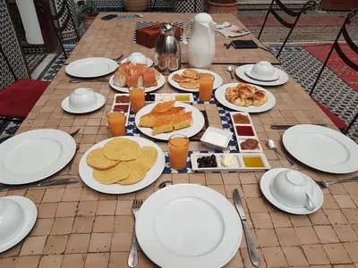 a table with white plates of food on it at Riad Jamaï in Fès