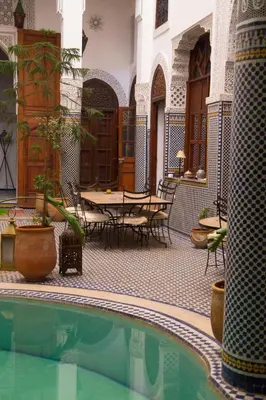 a courtyard with a pool and tables and chairs at Riad Jamaï in Fès