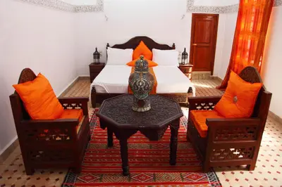 a bedroom with a bed and a table and two chairs at Riad Jamaï in Fès