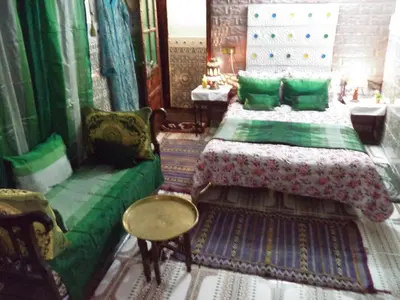 a bedroom with a bed with green pillows and a table at Dar Nouzha A in Fès