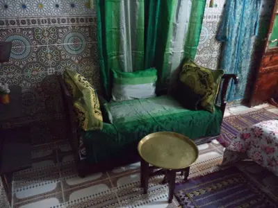 a room with a green chair and a table at Dar Nouzha A in Fès