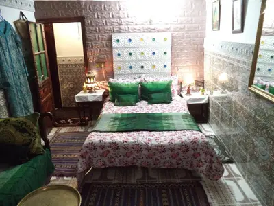 a bedroom with a bed with green pillows at Dar Nouzha A in Fès