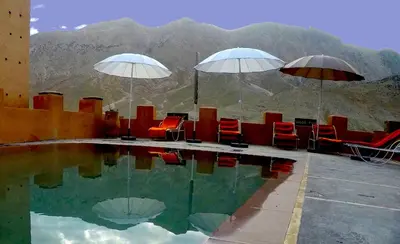 a pool with chairs and umbrellas on top of a mountain at La Kasbah du M'goun in Timit
